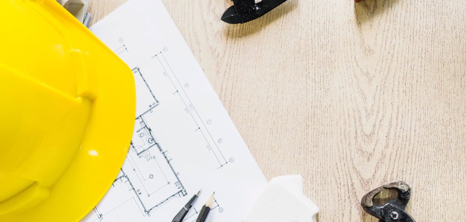 Yellow safety helmet with construction plans and tools